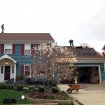 roofers on top of roof tearing off old roof shingles